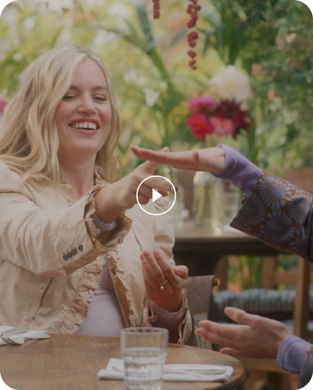 A clapperboard reveals Tom Hardy caressing a small dog, which he lifts onto his lap. He is wearing a grey jumper and glasses.
